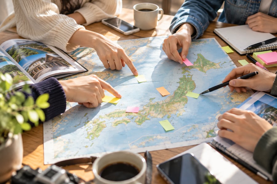 日本地図に付箋を貼り、卒業旅行の行き先を相談する大学生の手元